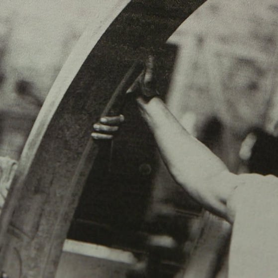 Archivbild: Zwei Arbeiter drehen ein schweres Rad