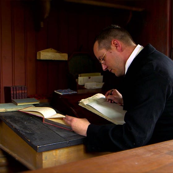 Händler dokumentiert seine Geschäfte am Schreibpult mit Feder und Tinte