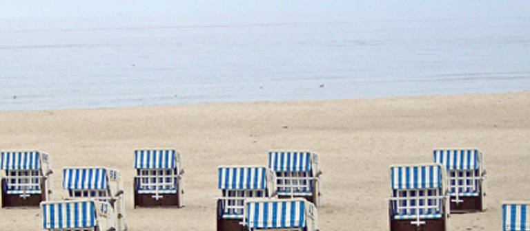 Ein Strand, an dem blau-weiße Strandkörbe stehen. (Foto: SWR – Screenshot aus der Sendung)