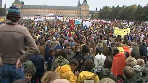 Friedenskundgebung Hofgarten Bonn; im Hintergrund: SchlossUniversität; im Vordergrund: Demonstranten von hinten (Foto: SWR - Screenshot aus der Sendung)