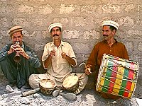 Drei Musiker sitzend an einer Hauswand