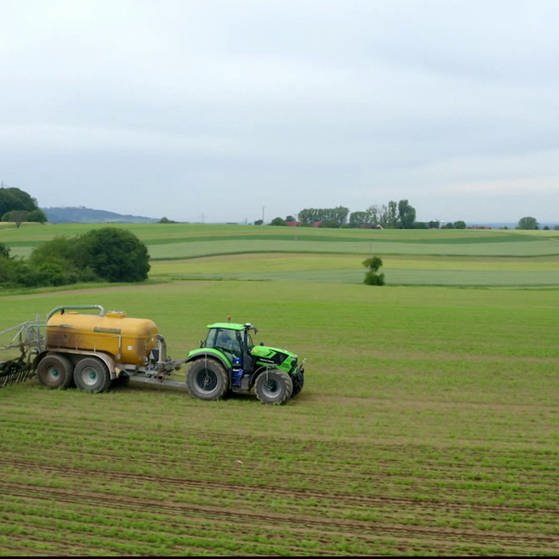 Traktor beim Ausbringen von Gülle auf Feld.