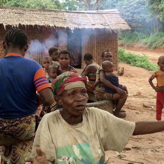 Dorf im Kongo : Menschen vor einer Hütte, im Vordergrund eine alte Frau.