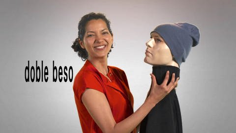Eine Frau hält einen Plastikkopf, neben ihr der Schriftzug "doble beso". (Foto: WDR)