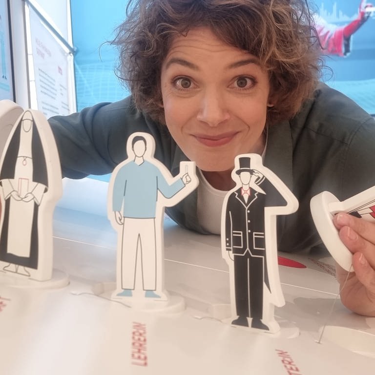 Moderatorin Lena Ganschow mit Pappfiguren, die verschiedene Berufe symbolisieren (Foto: SWR)