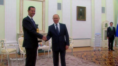 Assad und Putin schütteln sich in einem großen Saal die Hände und lächeln dabei in die Kamera (Foto: SWR)