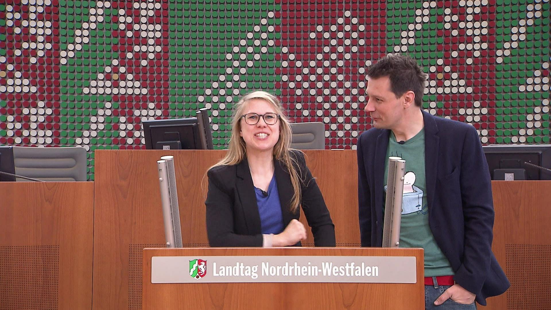 Ein Mann und eine Frau stehen im Landtag von Nordrhein-Westfalen an einem Pult.
