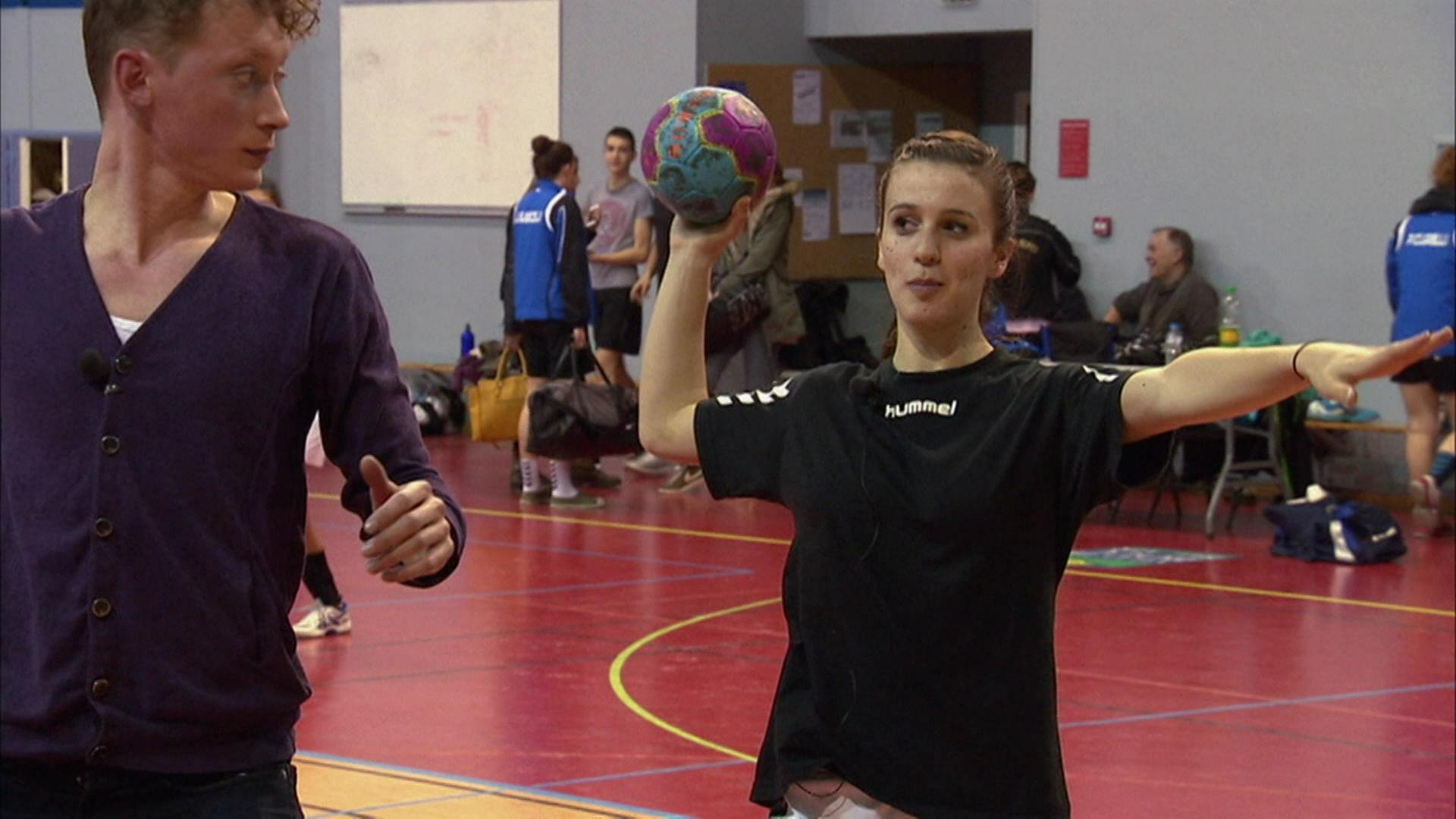 Zwei junge Menschen trainieren in einer Sporthalle Handball.