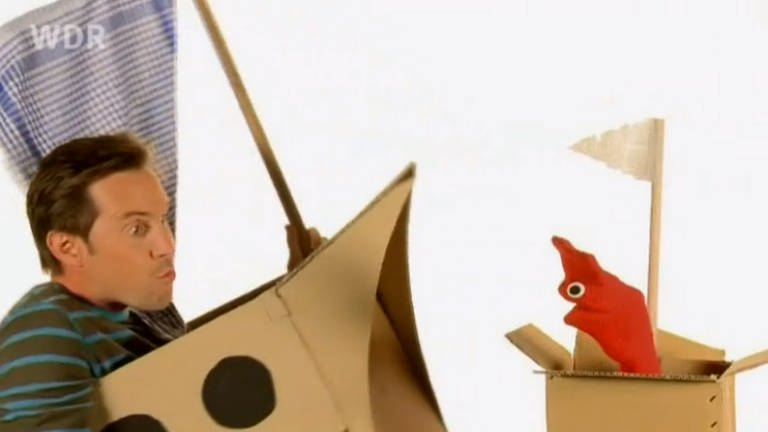 Englisch für die Grundschule: David und die rote Strumpfhandpuppe Red in Schiffen aus Pappe.