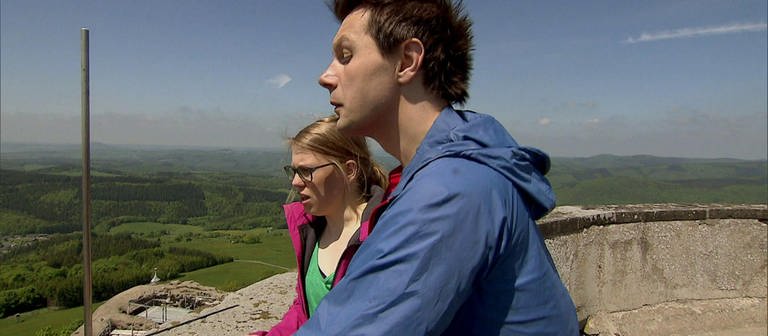 Ein Mann und eine Frau stehen auf einer Aussichtsplattform und schauen ins Tal hinab. (Foto: SWR / BR / WDR - Screenshot aus der Sendung)