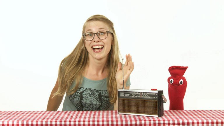 Zwischen Esther und der roten Socke steht ein Radio auf dem Tisch.