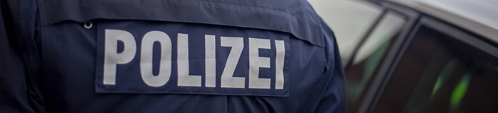 Schriftzug Polizei auf dem Rücken der Jacke eines Polizeibeamten (Quelle: imago / Deutzmann)