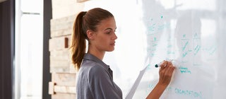 Eine Frau schreibt auf eine Tafel - Fortbildungen bei Planet Schule