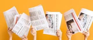 Zeitungen werden in die Höhe gehalten