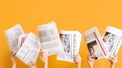 Zeitungen werden in die Höhe gehalten