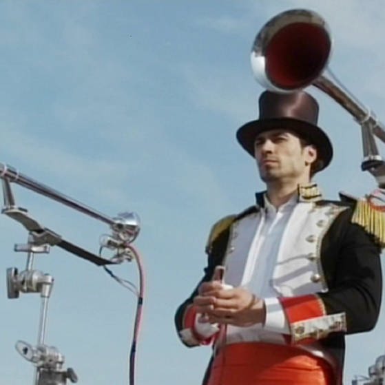 Ein Mann mit Zylinder zwischen zwei Pressluftfanfaren auf Stativen. (Foto: SWR – Screenshot aus der Sendung)