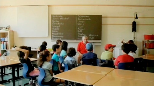 Schüler und Lehrer im Stuhlkreis in einem Klassenzimmer.
