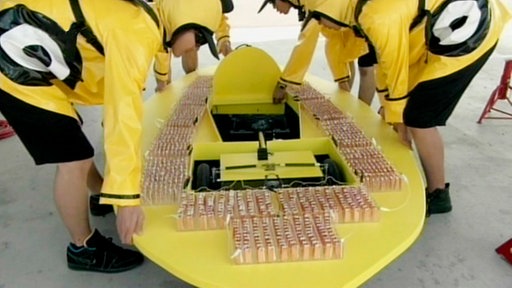 Gelbes, flaches Gefährt wird geschoben.