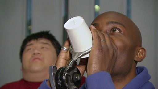 Mann spricht in ein Bechertelefon.