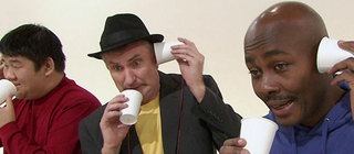 Drei Personen mit Bechertelefonen