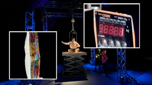 Zwei ineinandergesteckte Bücher, an den Buchrücken sind Metallaufhängungen angebracht.