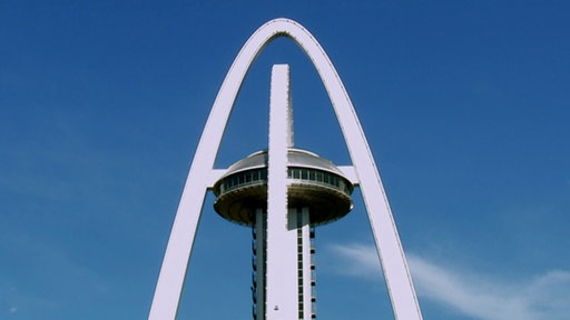 Spitze eines Turms mit zwei Stahlbögen.