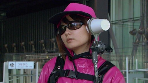 Frau mit Sonnenbrille an Bechertelefon.