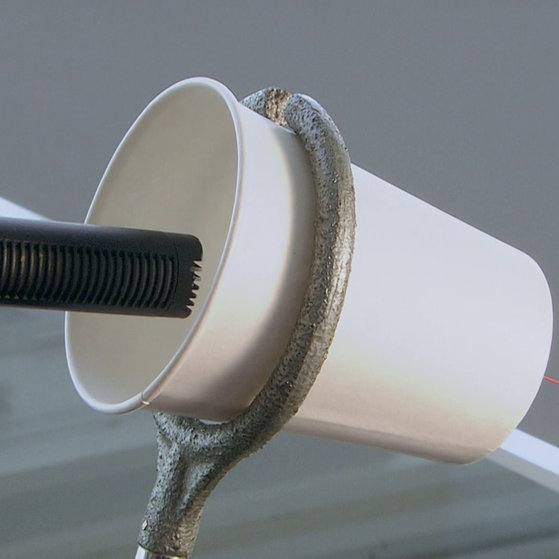 Mikrofon wird in einen Becher gehalten.