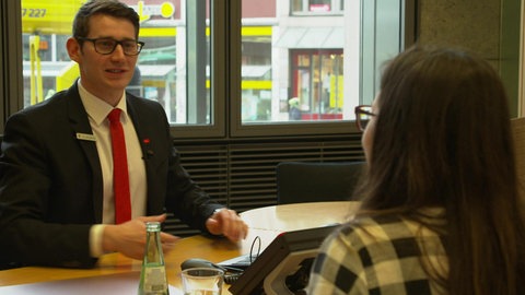 Ein Bankangestellter spricht mit einer Kundin. (Foto: WDR - Screenshot aus dem Film )