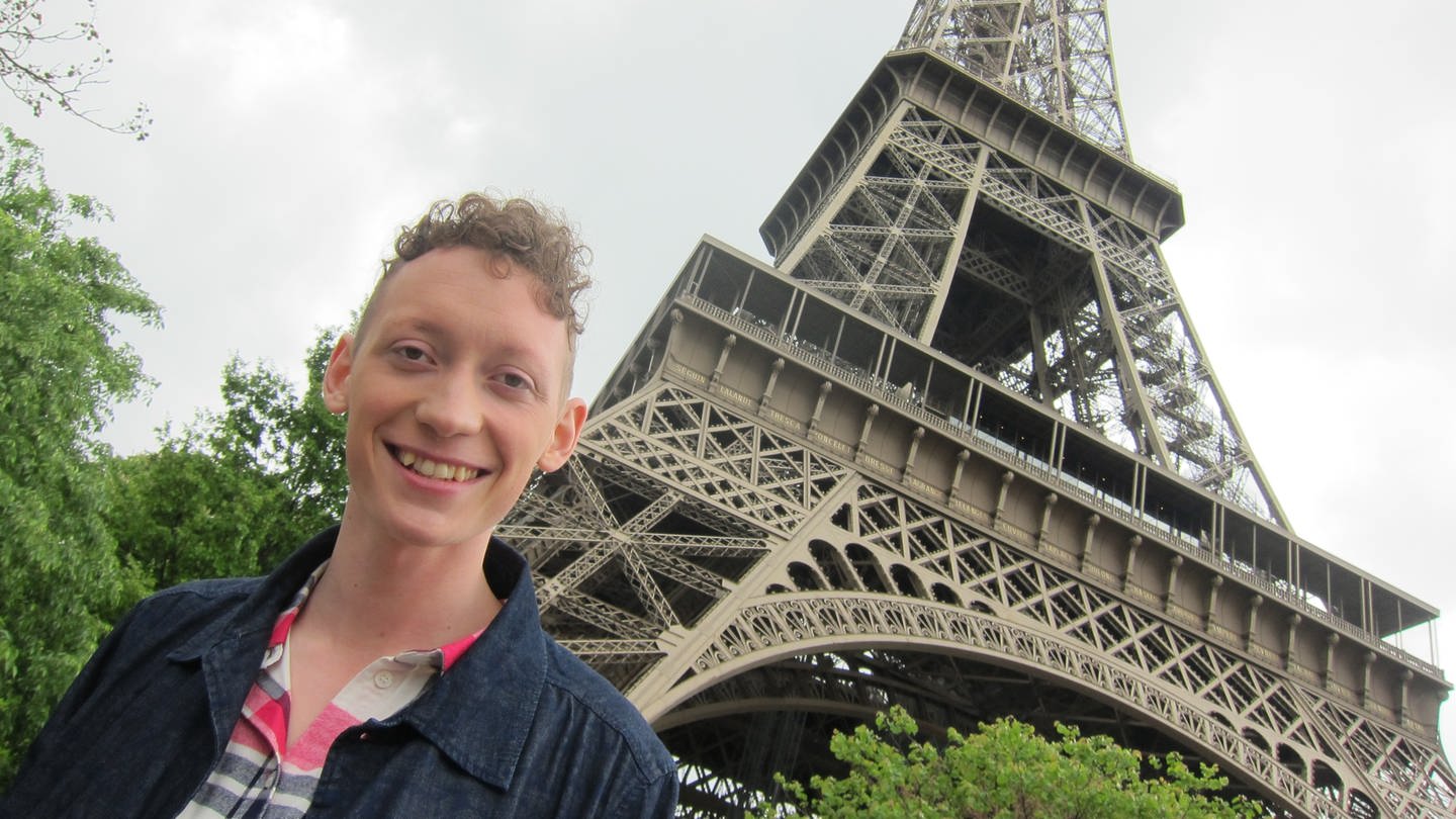 Junger Mann steht unterhalb des Eiffelturm. (Foto: WDR/UR)
