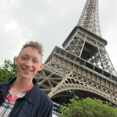 Ein junger Mann steht unterhalb des Eiffelturm. (Foto: WDR/UR)