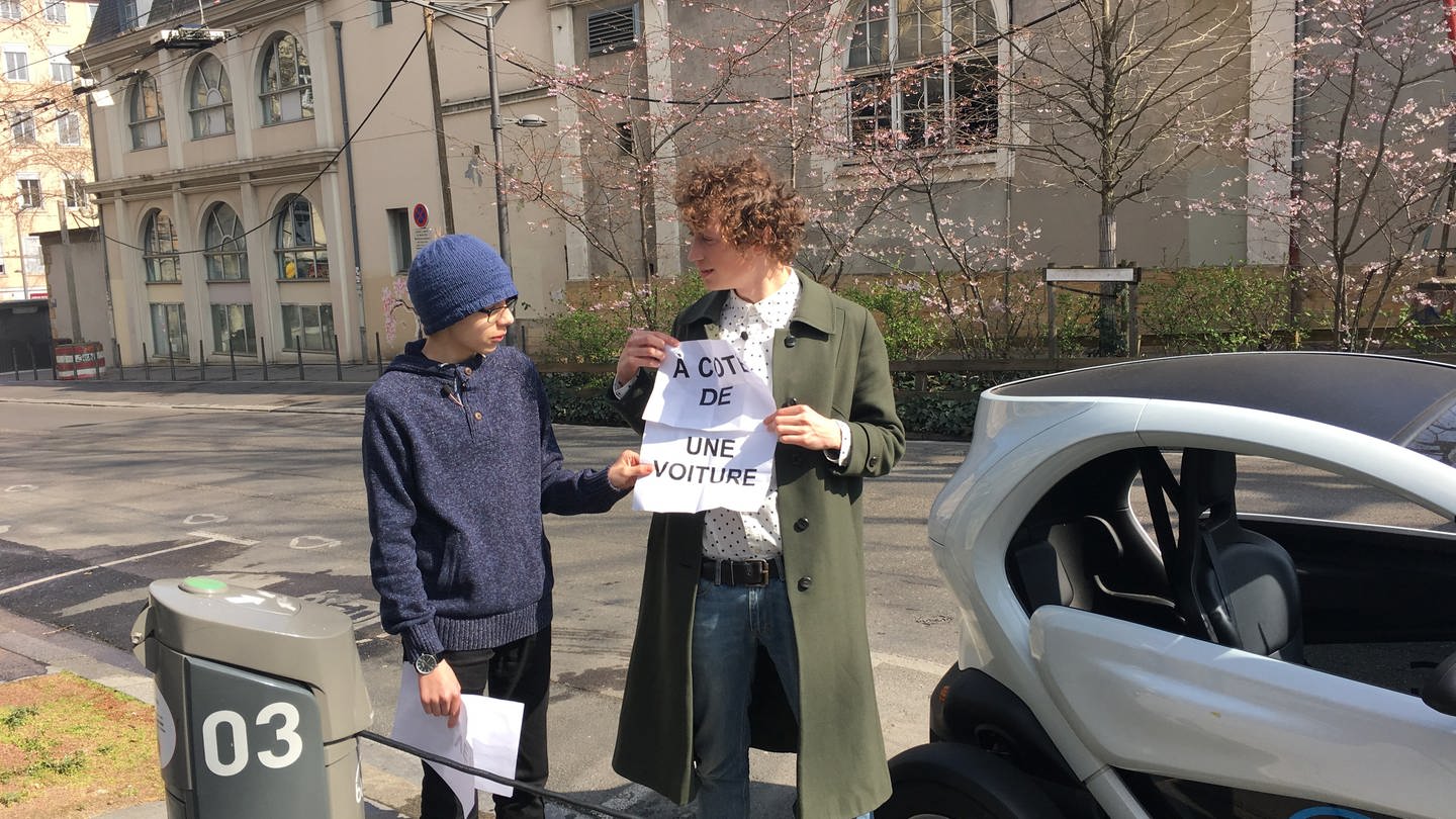 Ein junger Mann und ein Junge stehen neben einem Auto mit einem Zettel auf dem 