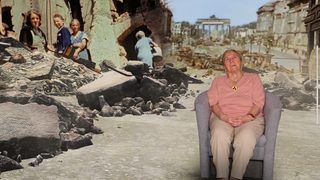 Eine ältere Dame sitzt in einem Sessel - im Hintergrund: Trümmer in Berlin (Screenshot aus der App)