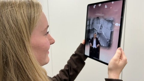 Eine Schülerin hält ein Tablet, auf dem ein Ausschnitt aus der App zu sehen ist. Rechte: WDR