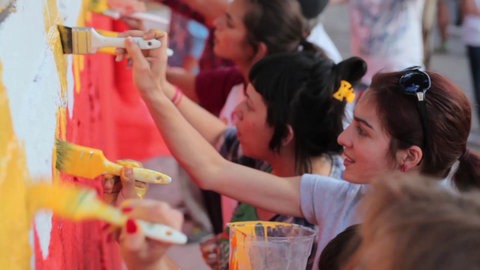 Frauen malen eine Wand an.