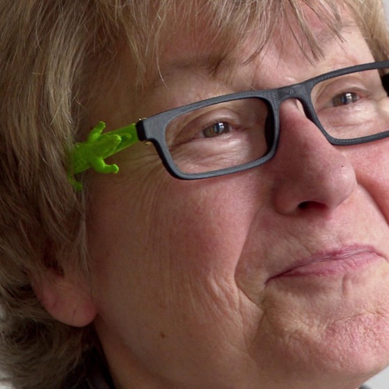 Frau mit Brille, auf dem Bügel ein grünes Krokodil.