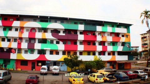 Farbig verzierter Wohnblock mit Schriftzug „Somos Luz“.