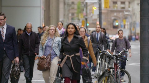 Mehrere Menschen laufen in einer Stadt.