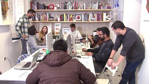 Mitglieder der Gruppe Boa Mistura um einen Arbeitstisch mit Laptops.