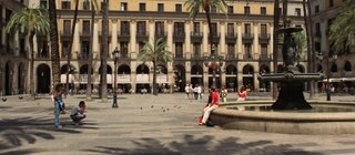 Ein Platz in Barcelona mit einem Brunnen und Palmen.