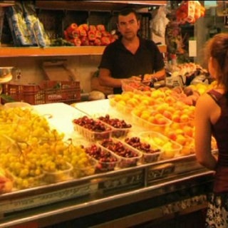 Eine junge Frau steht vor einem Obststand.