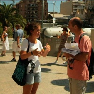 Ein Mädchen steht auf einem Platz und unterhält sich mit einem Mann.