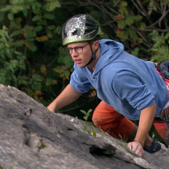Jonathan beim Klettern an einem Felsen. (Foto: SWR – Screenshot aus der Sendung „Jugendliche und Kirche“)