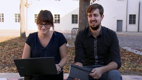 Lydia und Aaron sitzen vor dem Gebäude des Predigerseminars. (Foto: Screenshot aus der Sendung „Glaube und Kirche“)