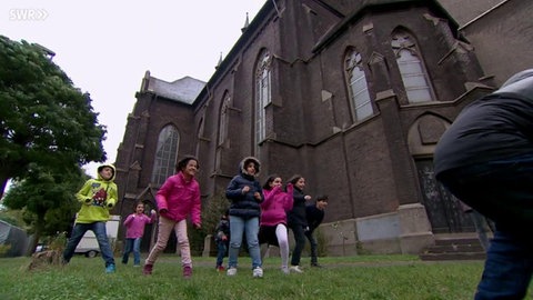 Kinder spielen auf dem Rasen vor einer Kirche.