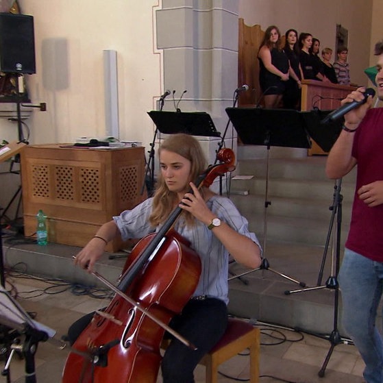 Jugendliche mit Musikinstrumenten in einer Kirche.