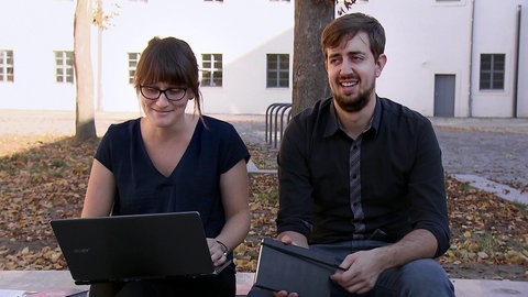 Lydia und Aaron sitzen vor dem Gebäude des Predigerseminars.