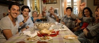 Menschen sitzen an einem gedeckten Tisch und lachen.