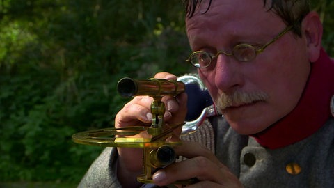 Ein Schauspieler verkörpert Tulla, der am Rhein steht und Messungen durchführt