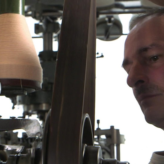 Textilfabrikant Rudolf Loder neben alter Spindel